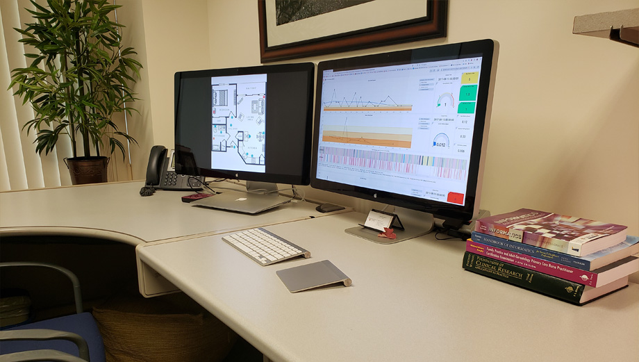 Two computers sit side-by-side on desk, lefthand one has home diagram and right-hand one has frequency data