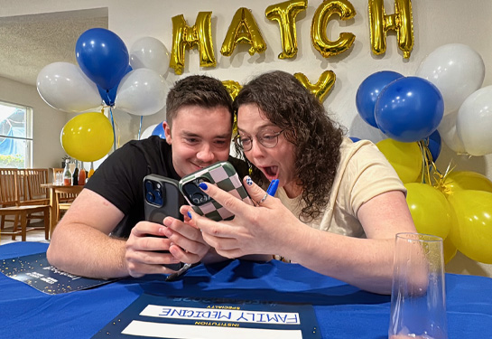 Two medical students react happily as they view their cell phones to learn they matched together at UCSF