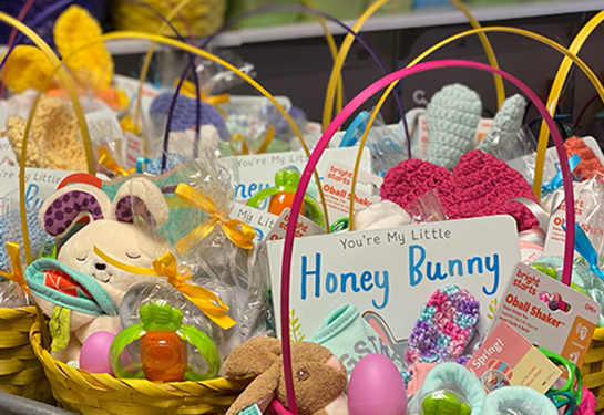 Baskets sit on a table, filled with plastic eggs, stuffed animals, books and toys.