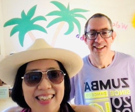 An image of Noriko and her husband, with a Hawaii themed wall backdrop