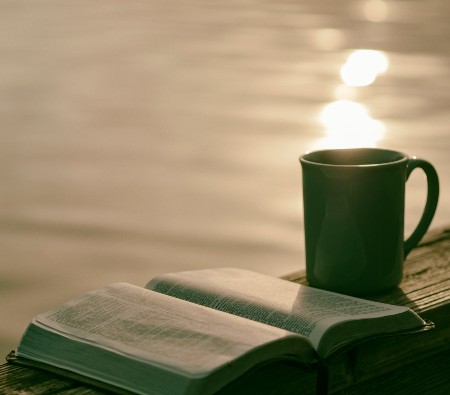Teal colored coffee mug placed on the edge of a bridge with the lake in the backdrop