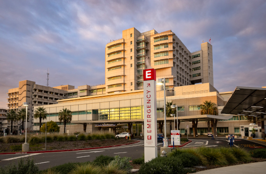A wide angle photo of the UC Davis medical center taken from the street at sunset.