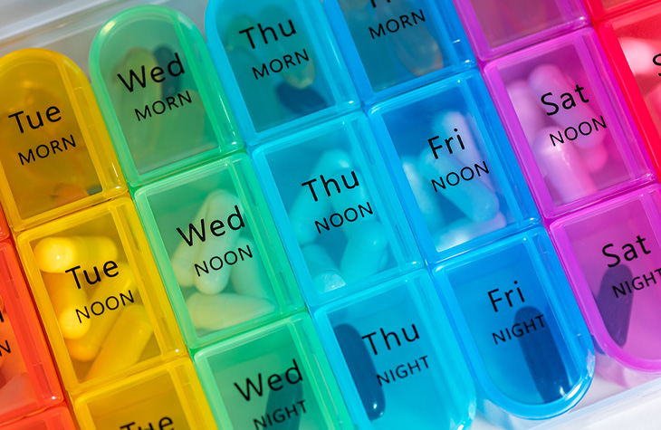 Color-coded pill organizer labeled by day and time, with medications stored in individual compartments.