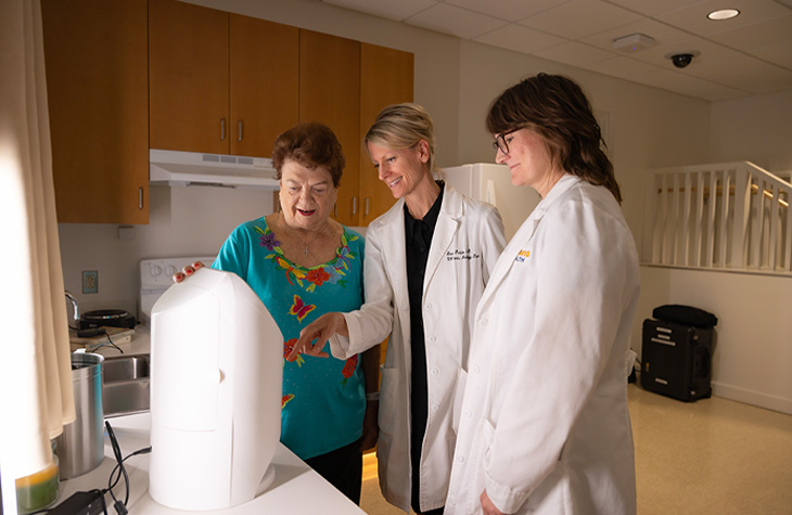 Three people review a smart medication dispenser together in a clinical testing space.