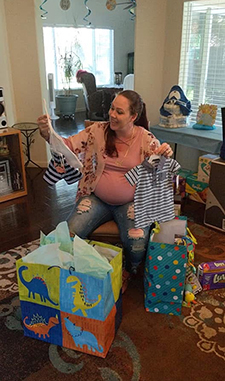 Pregnant woman sitting in a chair surrounded by gifts at her baby shower