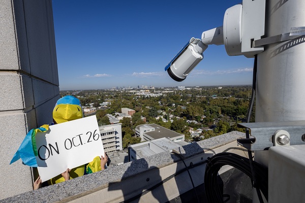 A falcon mascot holds a sign reading &ldquo;ON OCT. 26&rdquo; from the UC Davis Health rooftop.