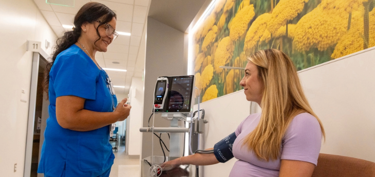 A patient has blood pressure monitored during an appointment by a member of the care team.