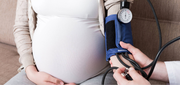 Pregnant person getting blood pressure checked on arm.