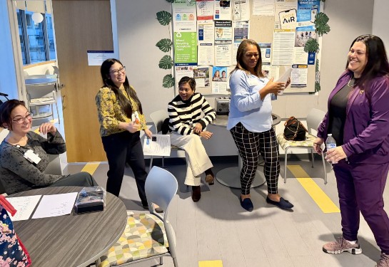 Employees participate in an interactive workplace team-building exercise in a staff lounge area.