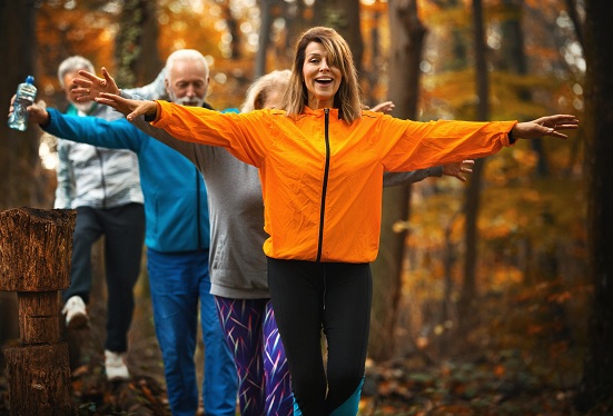 People practicing balance exercises on a wooded trail.
