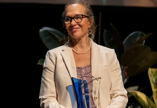Piri Ackerman stands holding award