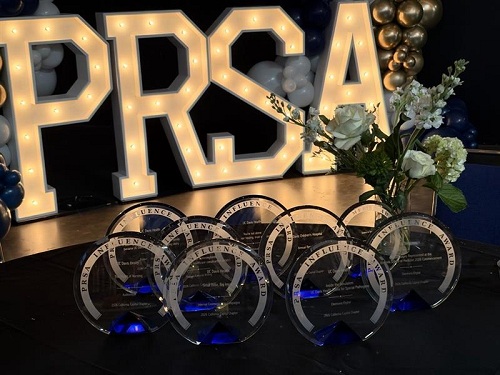 PRSA Influence and Merit awards displayed in front of illuminated PRSA letters at the awards ceremony.