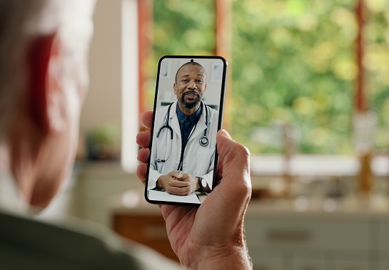 erson participates in a telehealth visit, viewing a health care provider on a smartphone screen.
