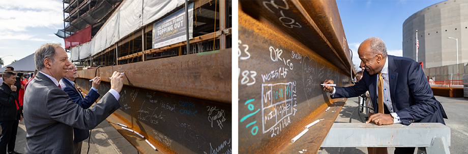 Mark Rosenblatt and Gary May use markers to sign the final steel beam during the California Tower topping out ceremony, with handwritten messages covering the beam.