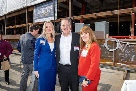 Associate Chief Operating Officer Kimberly Bleichner-Jones, interim CEO Mike Condrin, and Chief Nursing Executive Christine Williams pose in front of scaffolding at the California Topping Out ceremony. 