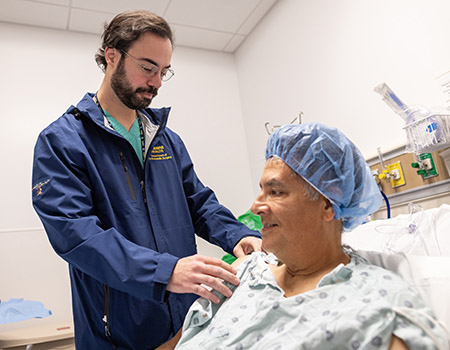 A surgeon in blue scrubs examines a patient who is ready for surgery