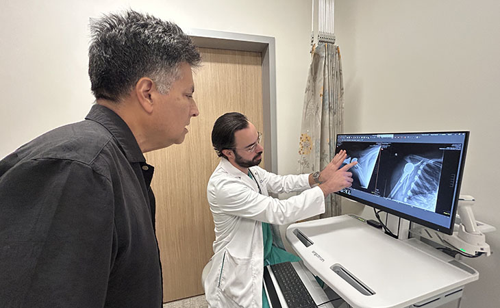 A patient looks over a physician's shoulder at his post-surgery xrays