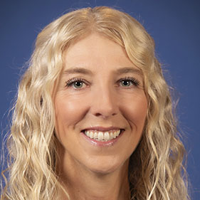 A professor with blonde hair poses for a portrait 