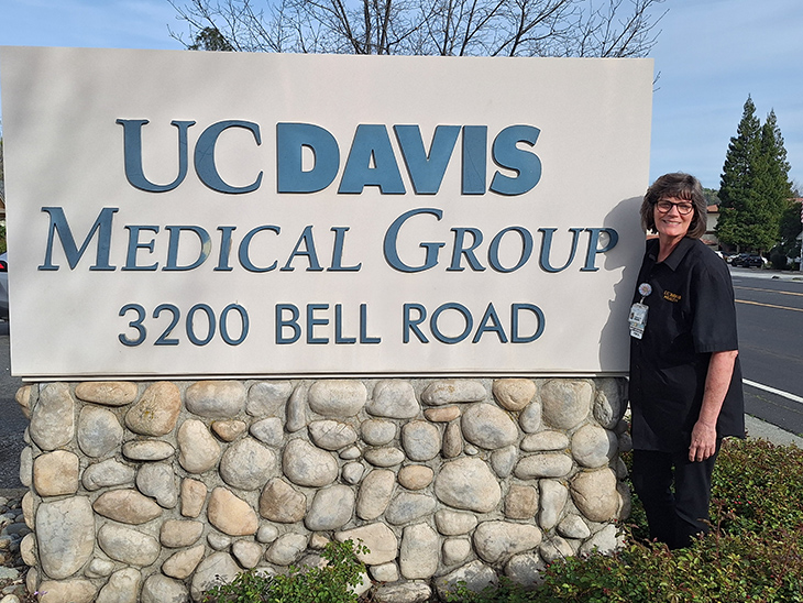 Woman standing outdoors next to UC Davis Health sign
