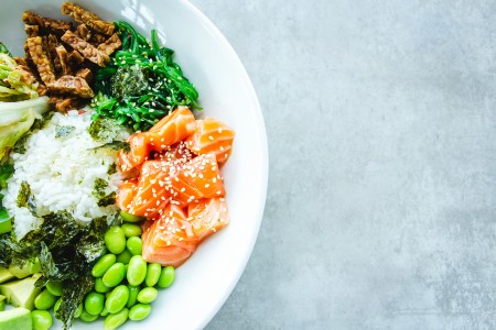 A white plate filled with colorful greens, legumes and fresh salmon 