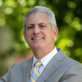 Portrait of person in suit against leafy backdrop