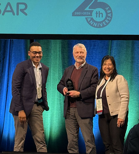 From left, Brian Boyd, David Amaral and Christine Wu Nordahl stand together on a stage at the INSAR conference.