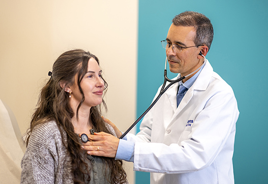 Primary care physician Victor Baquero uses a stethoscope to listen to a patient's heart and lungs