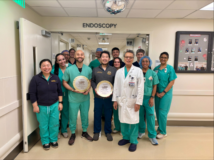 Team posing together wearing scrubs in a hospital hallway.