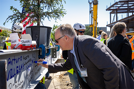 Mike Condrin, interim chief executive officer of UC Davis Health, signs the final steel beam at the Central Utility Plant topping out ceremony.