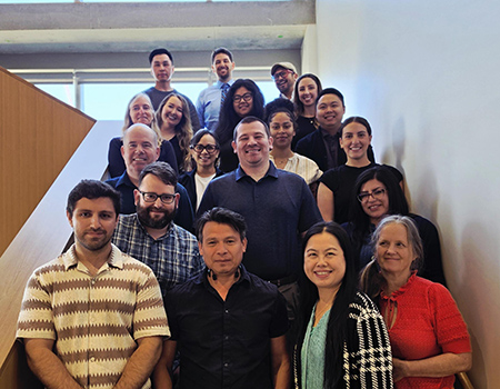Nineteen participants in the School of Medicine Training Certificate Program are standing on stairs and smiling at the camera.