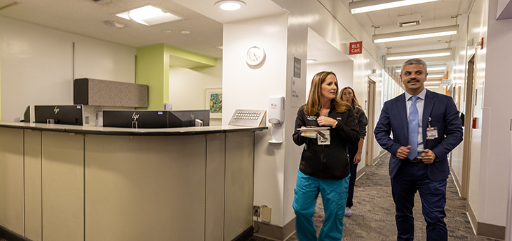Three people walk together in a clinic hallway 