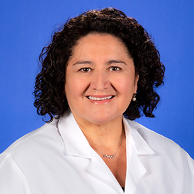 Headshot of a smiling woman with black hair wearing a white doctor's coat