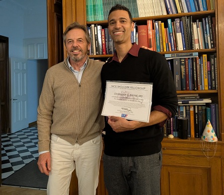 Two men pose for picture, one holds certificate of achievement.