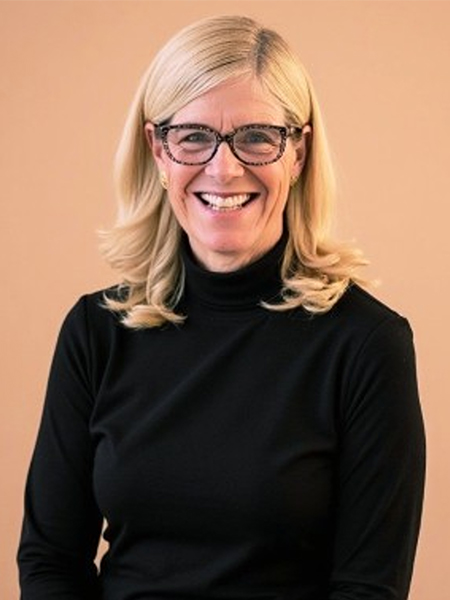 Portrait of a woman wearing glasses and a black turtleneck against a light brown background