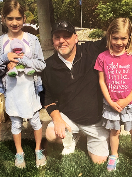 Photo of a man and two girls, one on each side of him