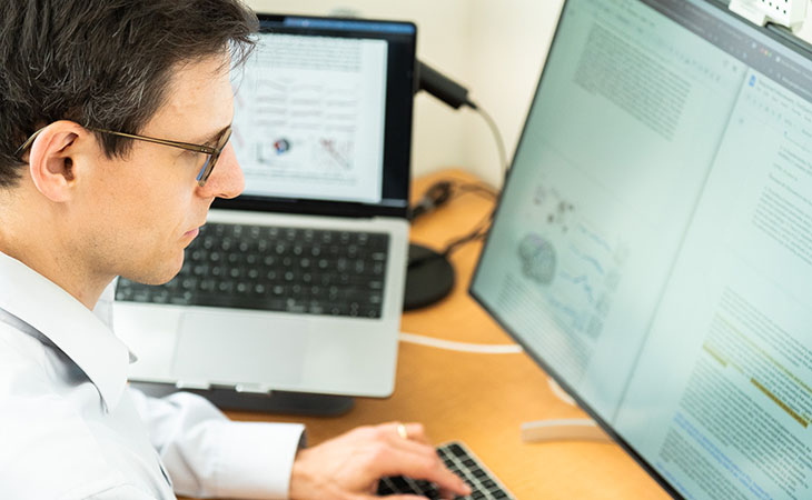 Sergey Stavisky sits at a desk, working on a computer in a lab. 