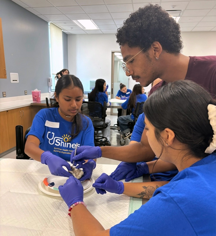  Students and a mentor wearing gloves work together on a hands-on anatomy activity during a simulation session.