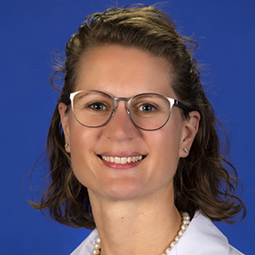 Headshot of a smiling woman with glasses in a white doctor coat