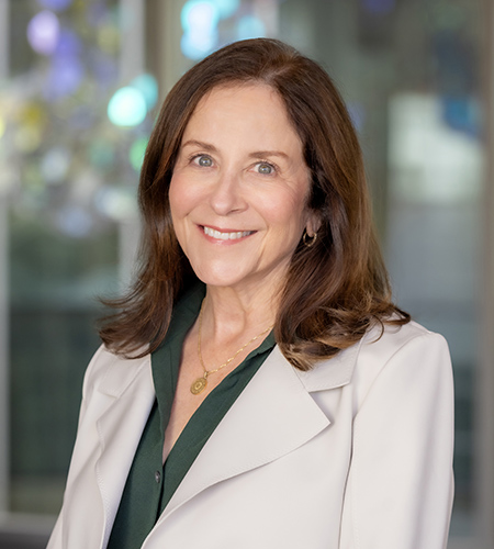 Susan Murin smiling in a green top and white blazer
