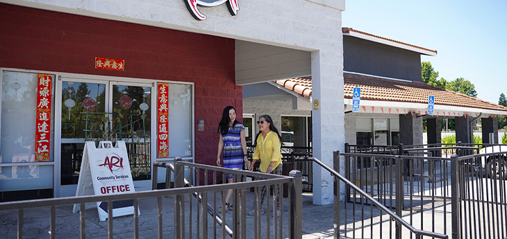 Two people walk outside the Asian Resources, Inc. community services office