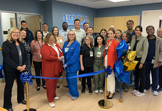 Large group of medical staff in front of blue ribbon, balloons in background