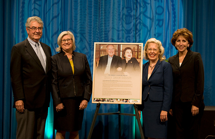 Four leaders pose beside a display honoring Betty Irene Moore at a UC Davis event.
