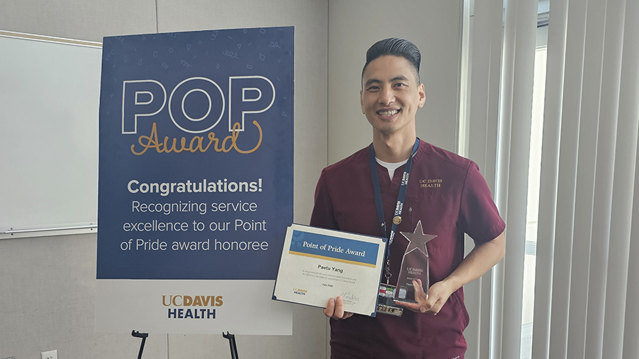 Clinician in scrubs holds trophy and certificate