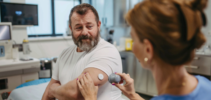 Healthcare clinician applying a continuous glucose monitor sensor on patient's arm.