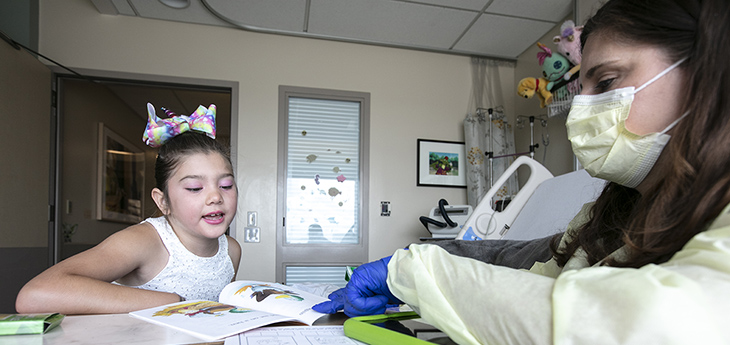 Sandra Morales reads a book, with help from her school teacher.