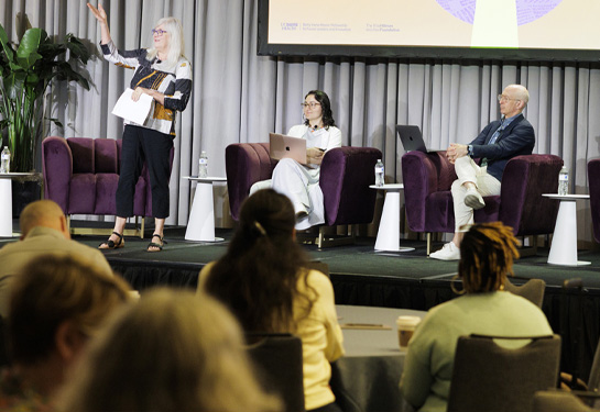 Panelists participate in a discussion onstage with a “Signal Through the Noise” presentation displayed behind them.