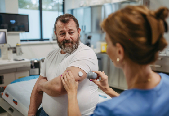 Healthcare clinician applying a continuous glucose monitor sensor on patient's arm.
