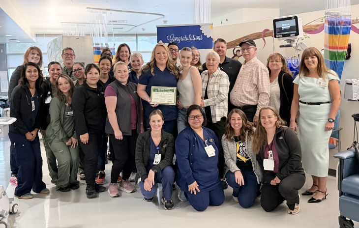 Large group of UCDH employees stand with Shellyn and her DAISY Award.