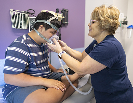 A person fits a CPAP mask on a child.