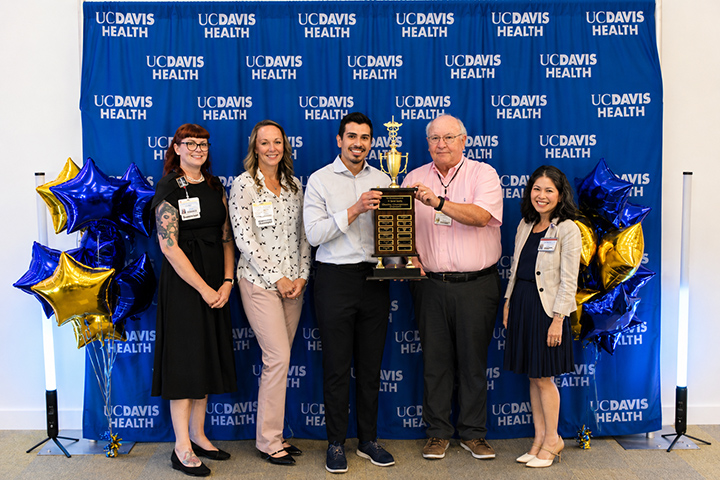 Group of employees pose with trophy